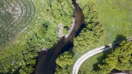 Aerial view of a river winding through wooded land and fields.