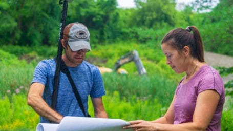 man and woman looking at engineering plan in an open area. Button Farm Colchester Vermont