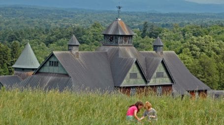 two children sitting in grass with large barn in the background