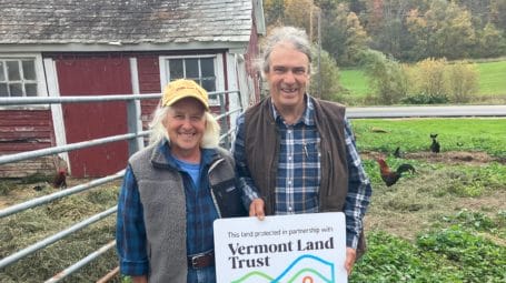 Joy and John with Vermont Land Trust sign on their farm
