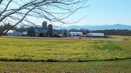 View across green pasture of farm buildings and silos - Addison, Vermont