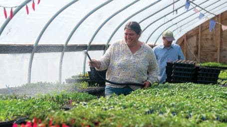 Christine watering plant starts in a greenhouse on Blue Heron Farm in Grand Isle Vermont