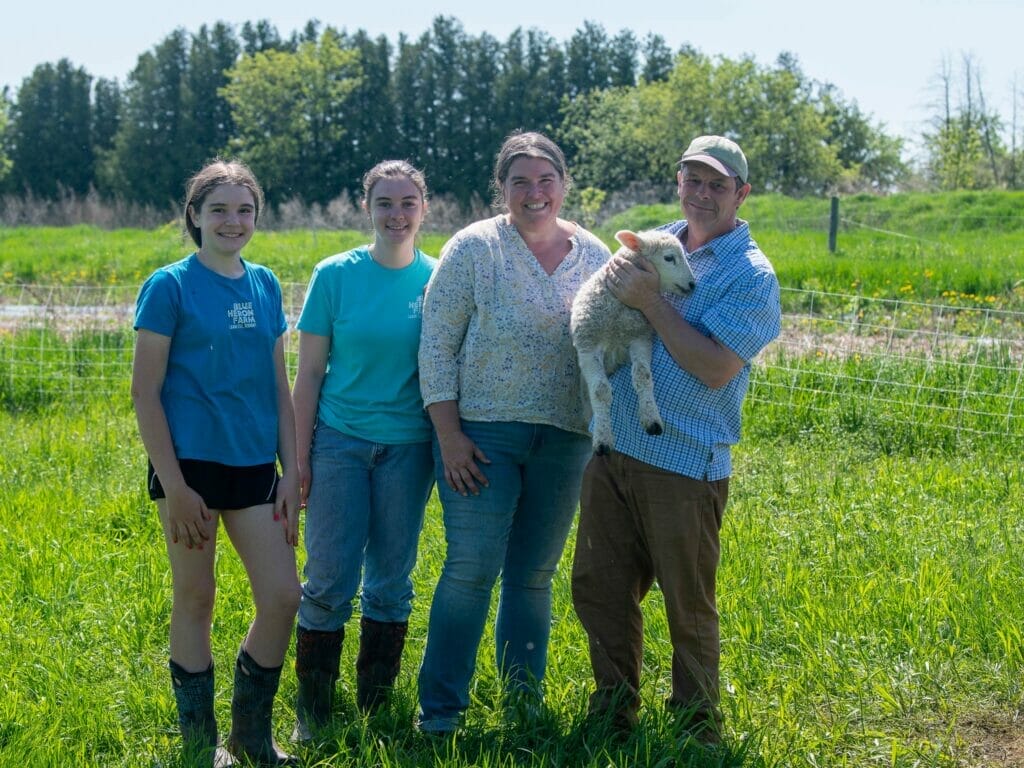 family of four at Blue Heron Farm holding a lamb on their Grand Island Vermont farm