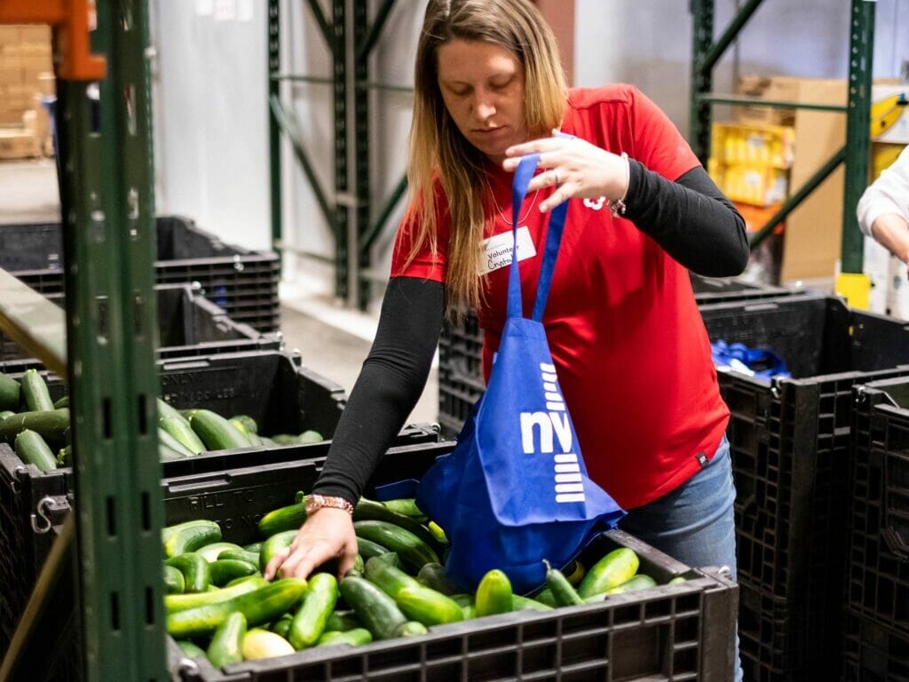 woman volunteering for Vermont Foodbank puts cucumbers in a bag