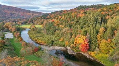 Aerial image of river with sandy beach area and forested hills with fall colors
