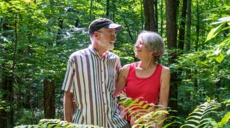 a couple looking at each other in the summer woods in vermont
