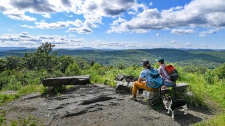 Two people sitting on a picnic table on Windmill Hill Pinnacle Ridgeline trail looking out a a huge view.