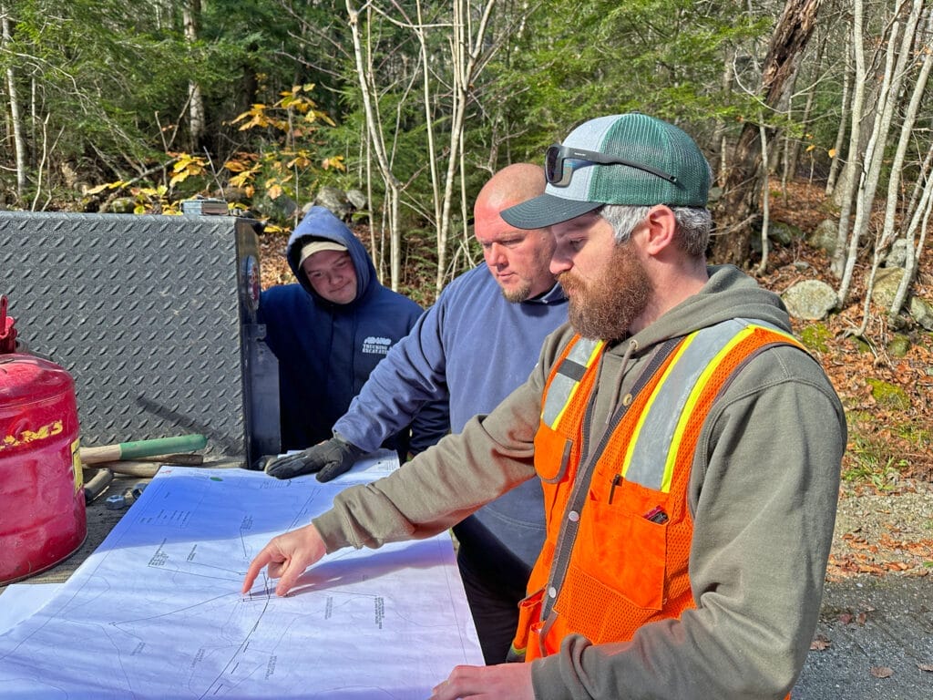 men in construction wear looking at technical plans. Stream crossing restoration Andover Vermont 
