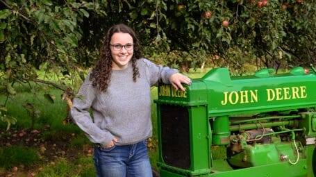 Picture of young person leaning on farm tractor