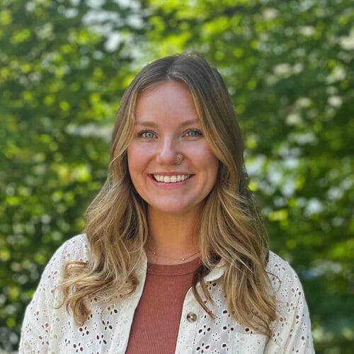 woman smiling at camera with trees in background