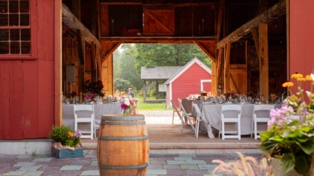 An open barn is filled with tables and chairs set up for a party